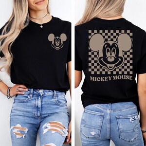 May include: Black t-shirt featuring a Mickey Mouse graphic on the front and back. The front has a small Mickey Mouse design, while the back showcases a larger Mickey Mouse design within a checkered pattern, with the words "MICKEY MOUSE" below.