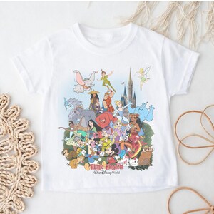 May include: White t-shirt featuring a colorful graphic of various Disney characters, including Dumbo, Peter Pan, and Mickey Mouse. The text "Magic Kingdom Walt Disney World" is printed at the bottom of the design. The shirt has short sleeves and a crew neck.