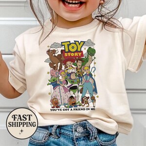 Puede incluir: Una camiseta color crema con un gr&aacute;fico colorido de personajes de la pel&iacute;cula "Toy Story". El dise&ntilde;o incluye a Woody, Buzz Lightyear y otros personajes, con las palabras "Toy Story" y "You've Got a Friend in Me".