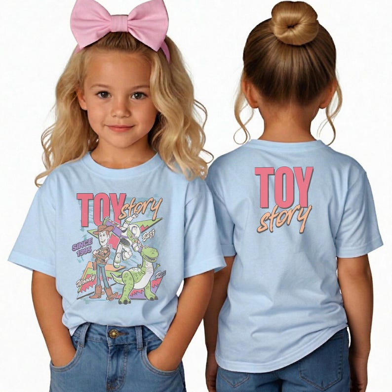 May include: Light blue t-shirts with a Toy Story graphic. The front of the shirt features Woody, Buzz Lightyear, and Rex. The back of the shirt has the words "TOY STORY" in pink and orange. The shirts are worn by a young girl.