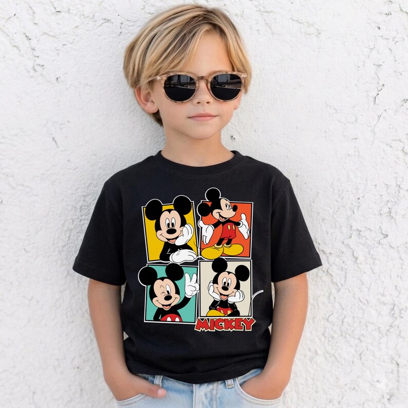May include: Black t-shirt with four panels displaying Mickey Mouse images. The panels have yellow, orange, green, and blue backgrounds. The word "Mickey" is printed in red at the bottom of the shirt.