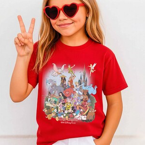 May include: A red t-shirt featuring a colorful graphic of Disney characters, including Mickey Mouse, Peter Pan, and Dumbo. The shirt has the text "Magic Kingdom Walt Disney World" at the bottom.