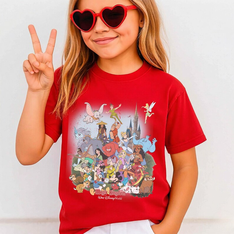 May include: A red t-shirt featuring a colorful graphic of Disney characters, including Mickey Mouse, Peter Pan, and Dumbo. The shirt has the text "Magic Kingdom Walt Disney World" at the bottom.