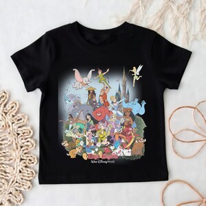 May include: Black t-shirt featuring a colorful graphic of various Disney characters, including Mickey Mouse, Peter Pan, and Dumbo. The graphic is set against a castle backdrop with the words "Magic Kingdom Walt Disney World".