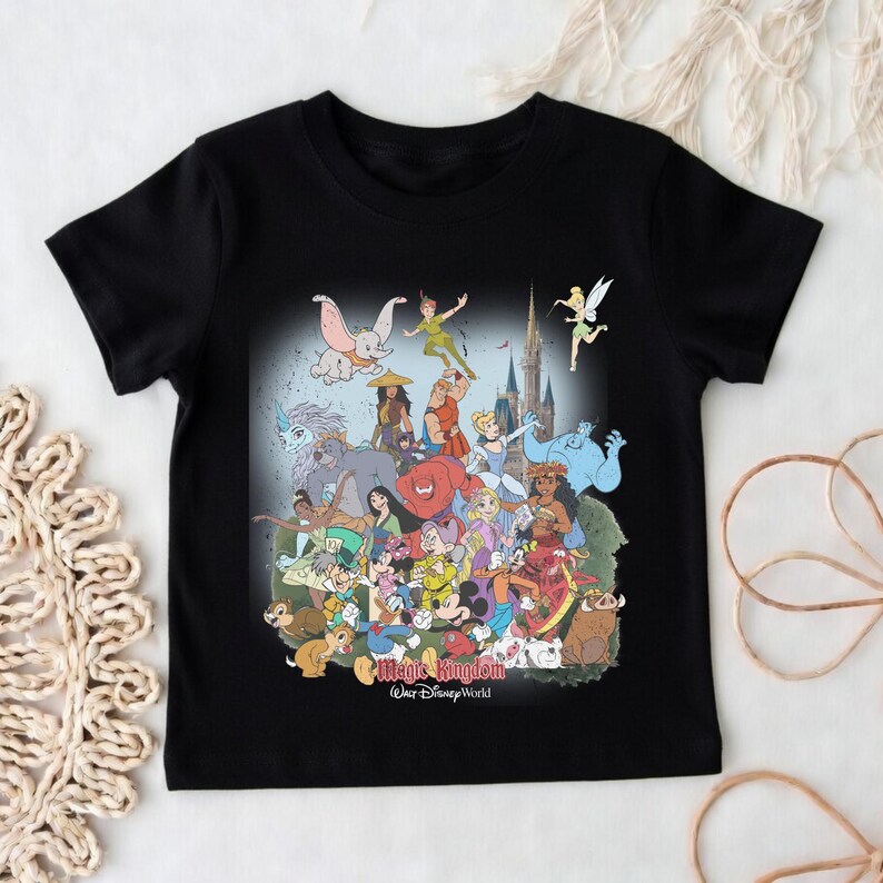 May include: Black t-shirt featuring a colorful graphic of various Disney characters, including Mickey Mouse, Peter Pan, and Dumbo. The graphic is set against a castle backdrop with the words "Magic Kingdom Walt Disney World".