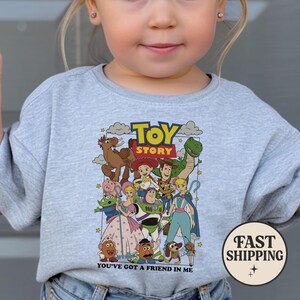 Puede incluir: Una sudadera gris claro con un gr&aacute;fico colorido de personajes de la pel&iacute;cula animada "Toy Story". El dise&ntilde;o incluye el t&iacute;tulo de la pel&iacute;cula y la frase "You've Got a Friend in Me".