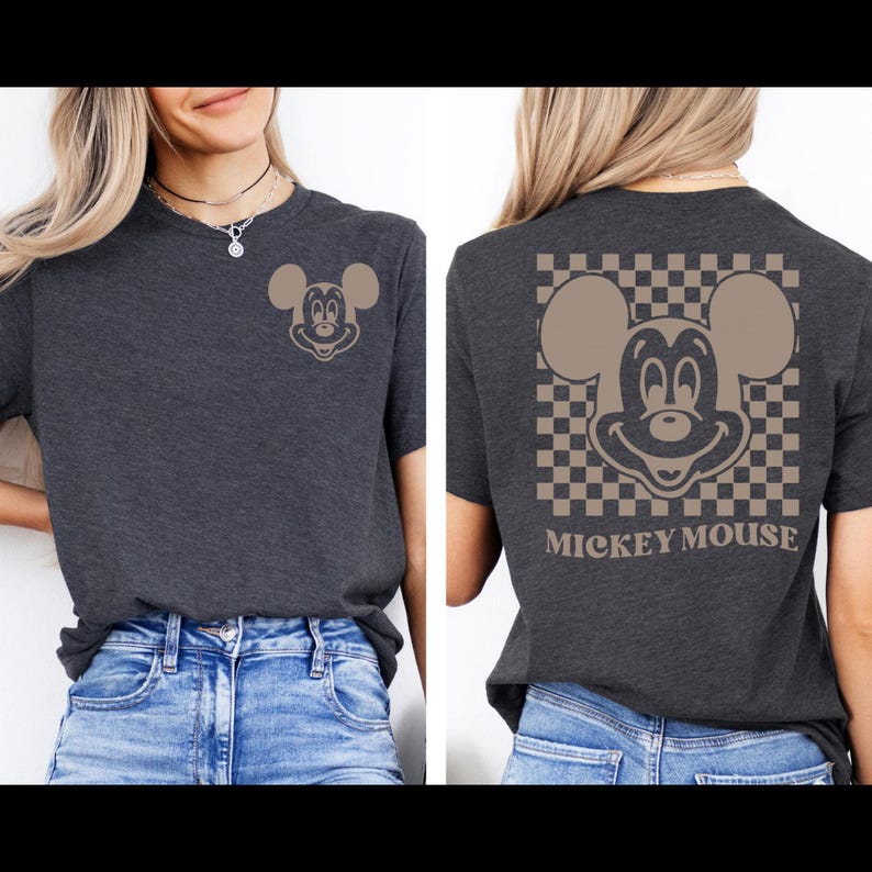 May include: Dark gray t-shirt featuring a tan Mickey Mouse graphic on the front and back. The back design includes a checkered pattern and the words "Mickey Mouse". The shirt is a casual style.