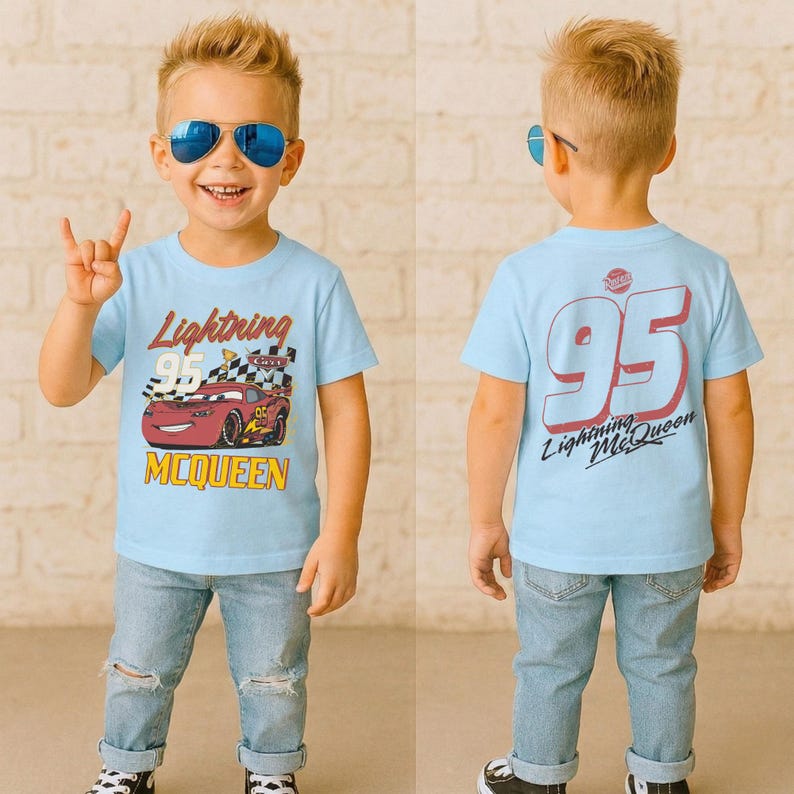 May include: A light blue t-shirt featuring Lightning McQueen from the movie Cars. The front of the shirt displays the text "Lightning McQueen" and "95" with a graphic of the race car. The back of the shirt has a large "95" and "Lightning McQueen" text.