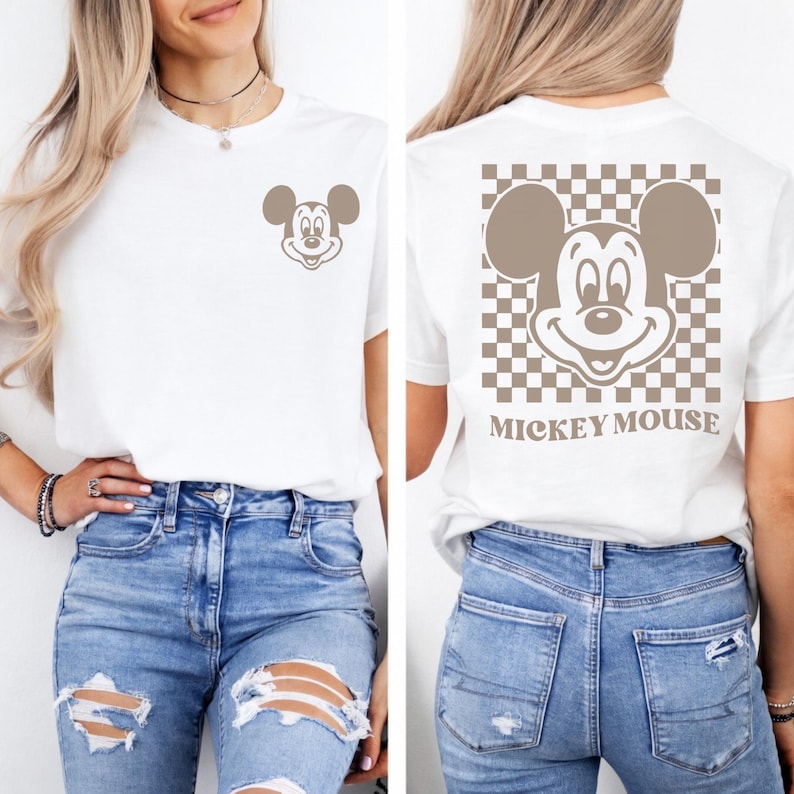 May include: White t-shirt featuring a Mickey Mouse graphic on the front and back. The front has a small Mickey Mouse head, while the back showcases a larger Mickey Mouse design with the words "MICKEY MOUSE" below it.
