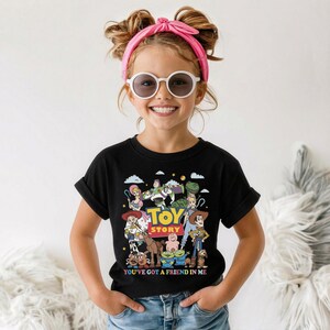 Op de afbeelding: Zwart T-shirt met een kleurrijke afbeelding van personages uit de film "Toy Story". Het ontwerp bevat de woorden "Toy Story" in geel en blauw, en de zin "You've Got a Friend in Me" onder de personages.