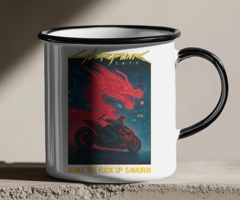 Puede incluir: Taza de esmalte blanco con borde y asa negros. La taza presenta un gr&aacute;fico vibrante de Cyberpunk 2077, que muestra un drag&oacute;n rojo, una persona en una motocicleta y el texto "WAKE THE FUCK UP SAMURAI".