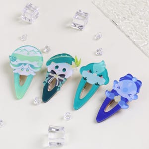 May include: Four colorful hair clips with cartoon character designs. The clips feature shades of blue and green, with intricate details. Each clip has a unique character design, including a cloud, a character with a hat, and a character with a bow.