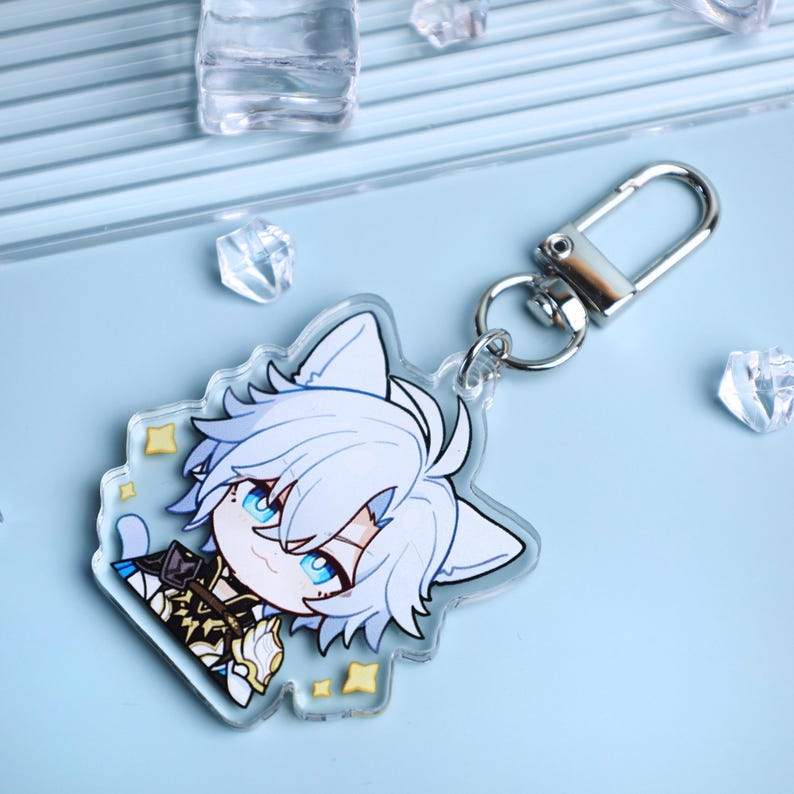 May include: Clear acrylic keychain featuring a cartoon character with white hair, blue eyes, and a cat-like appearance. The keychain has a silver clasp and a decorative shape with yellow star accents.