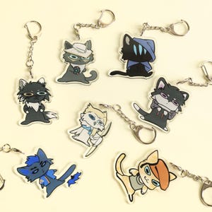 Peut inclure: Une collection de porte-clés sur le thème des chats avec divers designs. Chaque porte-clés présente un personnage de chat de dessin animé différent dans diverses poses et tenues. Les porte-clés sont en acrylique transparent et ont des anneaux de clés en métal argenté.