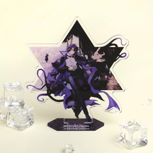 May include: A star-shaped acrylic stand featuring a character illustration in shades of purple and black. The character is dressed in a long coat and holds a book. The base of the stand has the text "Eternal Hymn".