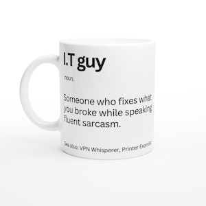 May include: White ceramic mug with the text "I.T guy" in black, followed by a definition. The definition reads: "Someone who fixes what you broke while speaking fluent sarcasm." Additional text: "See also: VPN Whisperer, Printer Exorcist."