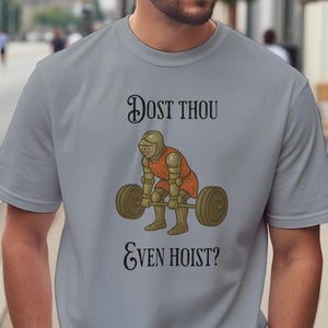 May include: A pale grey t-shirt with the words "Dost Thou Even Hoist?" above and below an illustration of a knight lifting weights. The knight is depicted in orange and gold armour.