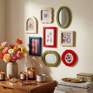 Puede incluir: Una colección de marcos de fotos decorativos en varias formas y colores, incluyendo rojo, azul, verde y crema. Algunos marcos presentan ilustraciones sencillas, mientras que otros tienen bordes ondulados. Los marcos están montados en una pared neutra.