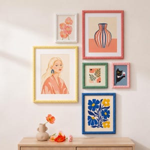May include: A gallery wall arrangement featuring six framed art prints with beaded frames in white, yellow, coral, green, pink, and blue. The prints depict floral patterns, a striped vase, a portrait of a person, and a black cat holding a glass.