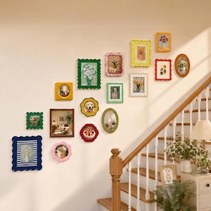 May include: A collection of various wall-mounted picture frames in diverse shapes, sizes, and colors, including scalloped, rectangular, and oval designs. The frames are arranged in a gallery display on a wall next to a wooden staircase.