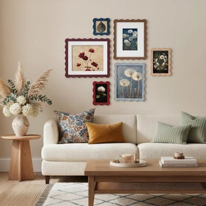 Könnte beinhalten: Ein Wohnzimmer mit cremefarbenem Sofa, Holztisch und gerahmten Blumendrucken. Dekorative Kissen in verschiedenen Mustern und Farben verschönern den Raum. Eine Vase mit Trockenblumen steht auf einem Beistelltisch.