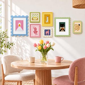 Könnte beinhalten: Eine Galeriewand mit sieben bunten, gewellten Bilderrahmen, die verschiedene Illustrationen wie eine Ente, eine karierte Tasse, einen Leoparden, einen Dalmatiner, einen Pudel, eine Katze mit Tasse und Bananen enthalten, über einem runden Holztisch.