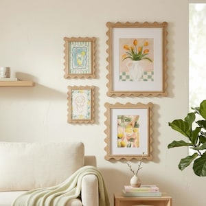 Puede incluir: Una composición de pared con cuatro marcos de madera clara con bordes festoneados. Los marcos contienen láminas artísticas que representan un vaso de limonada, un jarrón con tulipanes amarillos, un dibujo lineal de un rostro y una mano con bebida.