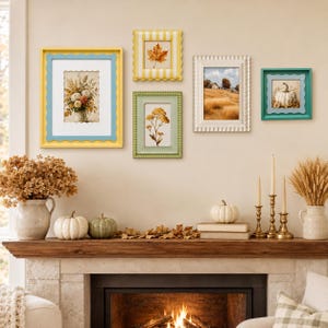 May include: A gallery wall arrangement featuring five rectangular picture frames in yellow, white, and green with scalloped edges. The frames contain prints of autumn foliage, a landscape, and a pumpkin. The display is above a wooden fireplace mantel.