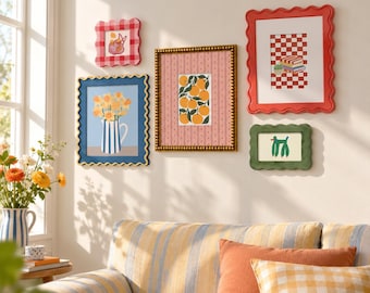 May include: A gallery wall arrangement featuring five framed art prints. The frames include a small red and white gingham square, a blue wavy frame with a floral print, a gold beaded frame with oranges, a large red wavy frame, and a small green wavy frame.