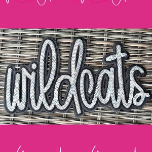 May include: A black and silver sequined patch with the word "wildcats" in a cursive font. The patch is outlined in black and has a white sequined border. The background is a woven texture with pink text that says "With Andi".