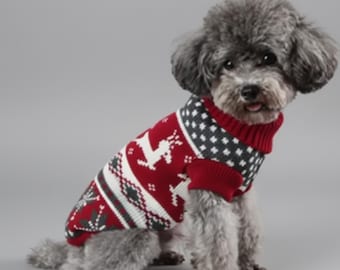 May include: A small dog wearing a red, white, and gray patterned sweater. The sweater features a reindeer design and a turtleneck collar. The dog is sitting against a gray background.