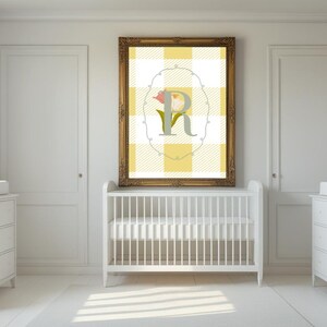 May include: A nursery scene with a white crib, dressers, and a framed artwork. The artwork features a yellow and white checkered background with a floral design and the letter "R". The room is painted white, creating a bright and airy atmosphere.