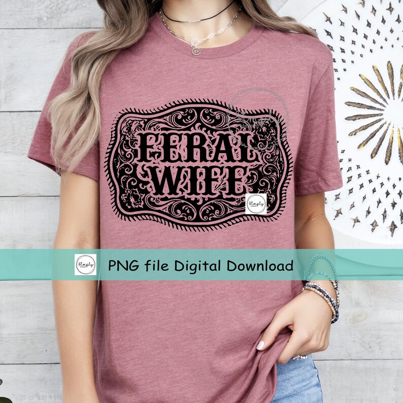 May include: A pink t-shirt with a black and white graphic of a belt buckle with the text "FERRAL WIFE" inside.