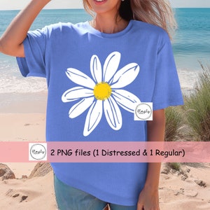 May include: A blue t-shirt with a white daisy graphic. The daisy has a yellow center. The text "2 PNG files (1 Distressed & 1 Regular)" is on a pink banner below the image.