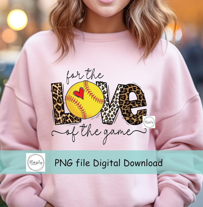 May include: Pink sweatshirt with the words "for the love of the game" in black text with a softball graphic in the middle of the word "love". The softball is yellow with red stitching and a red heart in the middle. The letters are surrounded by a leopard print pattern.