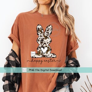 May include: A brown t-shirt with a white and brown cow print Easter bunny graphic and the text "happy easter". The text "PNG file Digital Download" is also included.