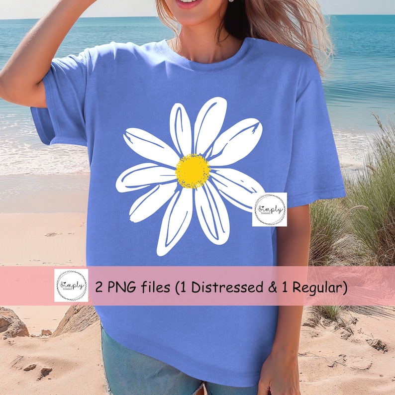 May include: A blue t-shirt with a white daisy graphic. The daisy has a yellow center. The text "2 PNG files (1 Distressed & 1 Regular)" is on a pink banner below the image.