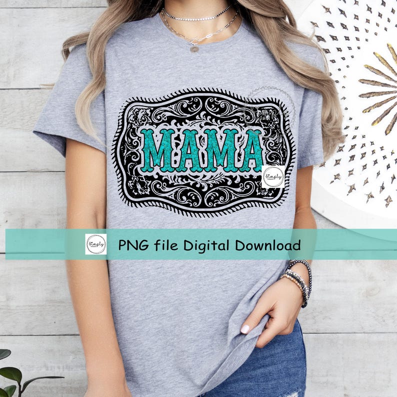 May include: A gray t-shirt with a turquoise and black graphic of a belt buckle with the word "MAMA" inside. The graphic has a vintage, distressed look.