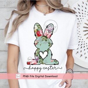 May include: A white t-shirt with a floral bunny graphic and the text "happy easter" in black script. The bunny is outlined in black and has a white heart in the center. The floral pattern is in shades of pink, green, and purple.