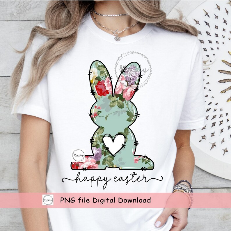 May include: A white t-shirt with a floral bunny graphic and the text "happy easter" in black script. The bunny is outlined in black and has a white heart in the center. The floral pattern is in shades of pink, green, and purple.
