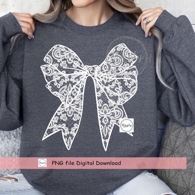 Puede incluir: Un dise&ntilde;o de lazo de encaje blanco sobre una sudadera gris oscuro. El dise&ntilde;o es un lazo grande con detalles intrincados. La sudadera es de cuello redondo con mangas largas. El texto "PNG file Digital Download" est&aacute; en la parte inferior de la imagen.