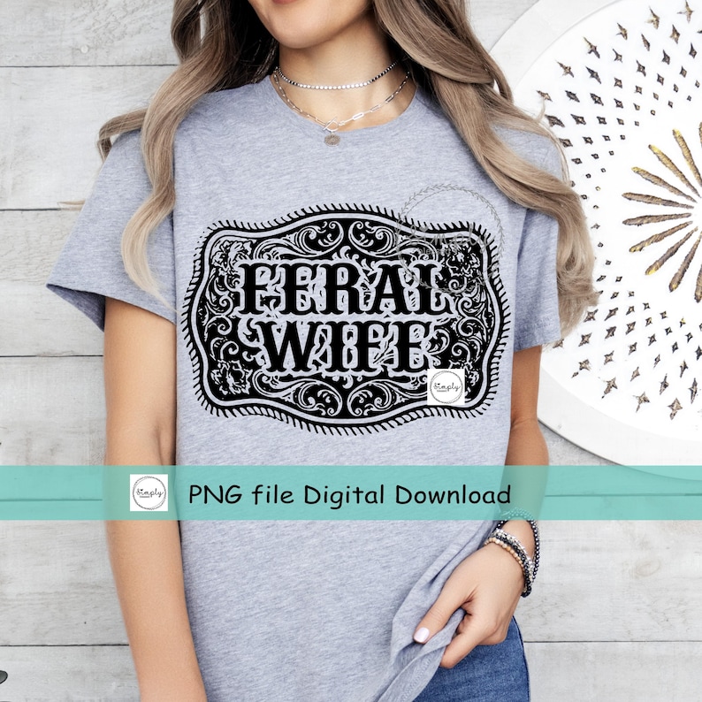 May include: A gray t-shirt with a black and white graphic of a belt buckle with the text "Feral Wife" inside.