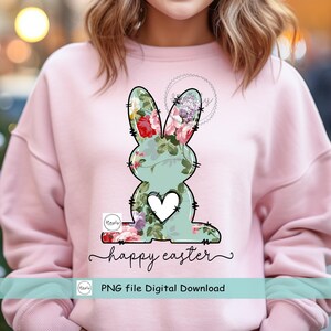 May include: A digital download of a floral bunny graphic with a heart in the center. The bunny is outlined in black and has a light blue background. The text "happy easter" is written below the bunny. The text "PNG file Digital Download" is written below the text "happy easter".