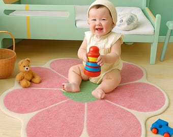 Peut inclure: Un bébé est assis sur un tapis rose en forme de fleur, tenant un jouet à empiler coloré. La pièce comprend un lit vert menthe, un ours en peluche et une voiture jouet bleue. Des papillons décorent le mur, créant une ambiance de chambre d'enfant.