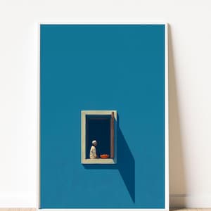 May include: Framed art print depicting a person in white attire seated in a window, with an open view to a dark interior and a bowl of oranges. The artwork is set against a vivid blue wall.