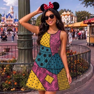 May include: A sleeveless dress featuring a patchwork design with various patterns including yellow with black dots, pink with black swirls, teal with black dots, and yellow with a black grid. The dress has a round neckline and a flared skirt silhouette.