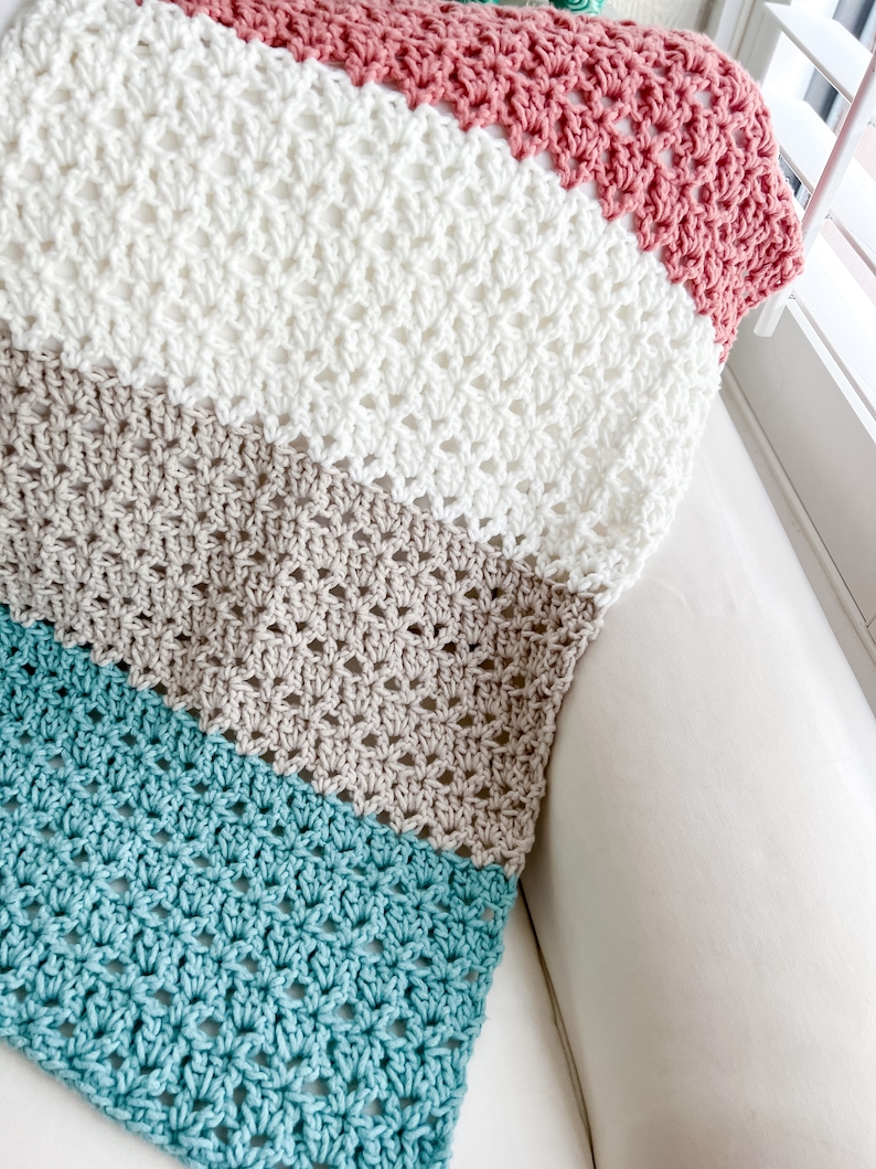 Pu&ograve; includere: Una coperta all'uncinetto con strisce turchesi, beige, bianche e rosa.