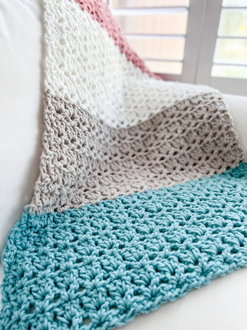 Pu&ograve; includere: Una coperta all'uncinetto con strisce bianche, beige, rosa e turchese.