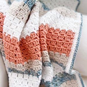 May include: A crocheted blanket with stripes of white, beige, light blue, and peach.