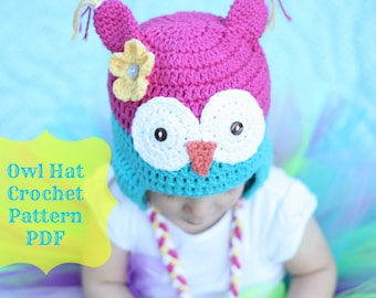 May include: A handmade crochet owl hat in pink, teal, and white, with a yellow flower accent. The hat features large white eyes with black button pupils and a small orange beak. The text "Owl Hat Crochet Pattern PDF" is in a yellow bubble.